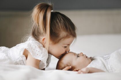 elder-sister-is-kissing-little-baby-girl-forehead-with-closed-eyes